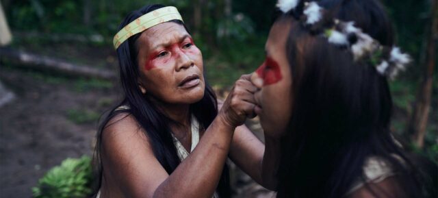 Ur-Einwohner des Amazonas-Regenwalds Ecuador mit Federschmuck und traditioneller Gesichtsbemalung